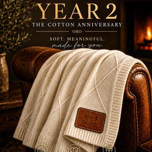 May include: A cream-colored cotton knit throw blanket featuring a diamond pattern and a brown leather patch embossed with the text E + J Est. 2024. The text CELEBRATING YEAR 2 THE COTTON ANNIVERSARY SOFT. MEANINGFUL. made for you. is visible above.