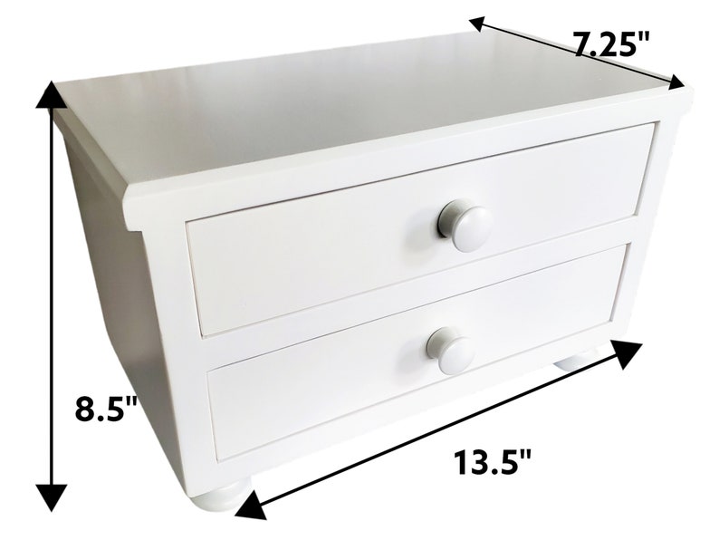 May include: A white wooden desktop organizer featuring two horizontal drawers with round knobs. The unit measures 13.5 inches in width, 8.5 inches in height, and 7.25 inches in depth, as indicated by the black dimension arrows on the image.