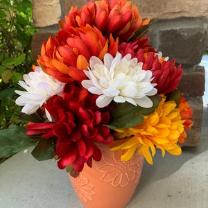 Fall floral autumn Arrangement. Beautiful, fall centerpiece. With orange, red, white, and yellow for flowers with orange vase.