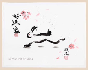 May include: A white print featuring a black ink illustration of a running rabbit with cherry blossoms. The artwork includes Chinese characters and the text "Yasa Art Studios".