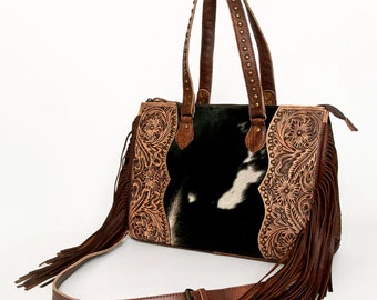 May include: A brown leather handbag with a black and white cowhide patch and fringe detailing. The bag has a top handle and a shoulder strap.