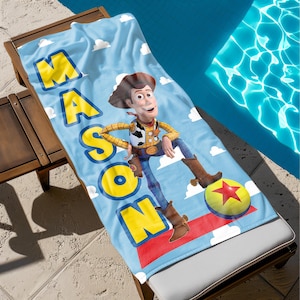 May include: A blue beach towel with a cartoon image of Woody from Toy Story. The towel has the name "MASON" written in yellow letters.