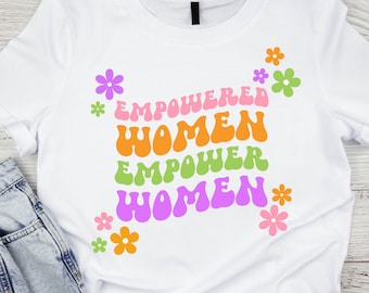 May include: White t-shirt with a graphic design featuring the text "Empowered Women Empower Women" in a retro font with colorful flowers.