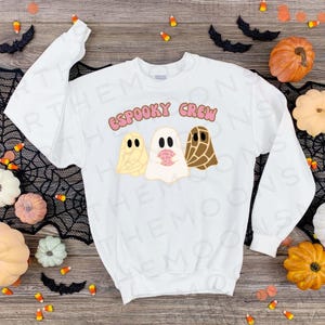 May include: White sweatshirt with the text "ESPOOKY CREW" in pink letters. Three ghosts are illustrated on the sweatshirt, one is yellow, one is white with pink accents, and one is brown.