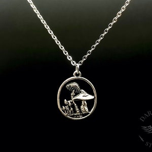 May include: Silver necklace with a round pendant featuring a detailed mushroom design. The pendant is surrounded by a circle.