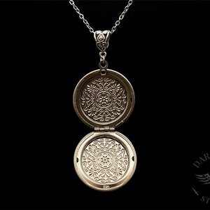 May include: Silver locket necklace with an intricate floral design on the front and back. The locket is open, revealing the inside.