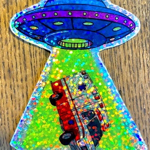 以下が含まれることがあります： 青と紫のUFOが赤と白の救急車を照らしているホログラフィックステッカーです。