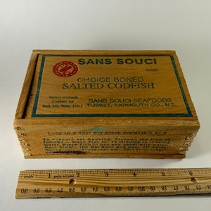 May include: A wooden box with a label that reads "Sans Souci Brand Choice Boned Salted Codfish." The label also includes the company name "Sans Souci Seafoods" and the location "Tusket, Yarmouth Co., NS."