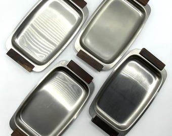 May include: Set of three silver serving trays with wooden handles. The trays are rectangular and have a polished finish.