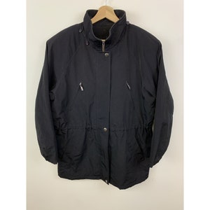 May include: A black, long-sleeved jacket with a zipper and button closure. The jacket has a drawstring waist and two zippered pockets on the front.