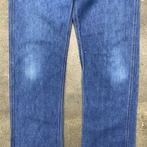 May include: A pair of blue denim jeans with a straight leg fit. The jeans have a classic look and are made from a durable material.