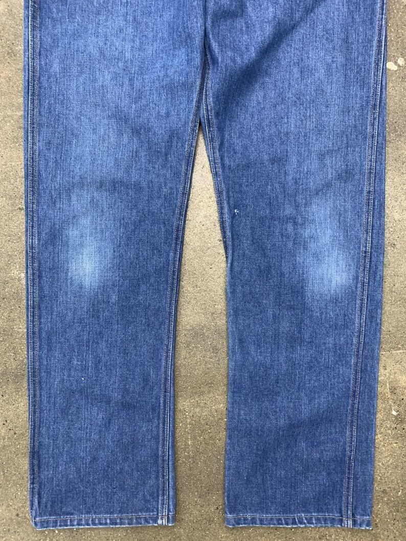 May include: A pair of blue denim jeans with a straight leg fit. The jeans have a classic look and are made from a durable material.