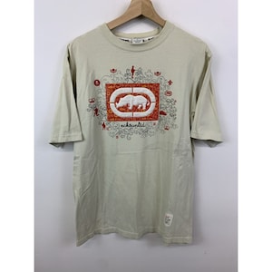 May include: A beige short-sleeved t-shirt with a graphic print of a white rhinoceros in a red and orange frame. The graphic also includes the text "ecko unltd".