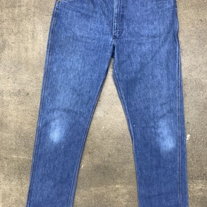 May include: A pair of blue denim jeans with a straight leg fit. The jeans have a classic five-pocket design and a button fly.