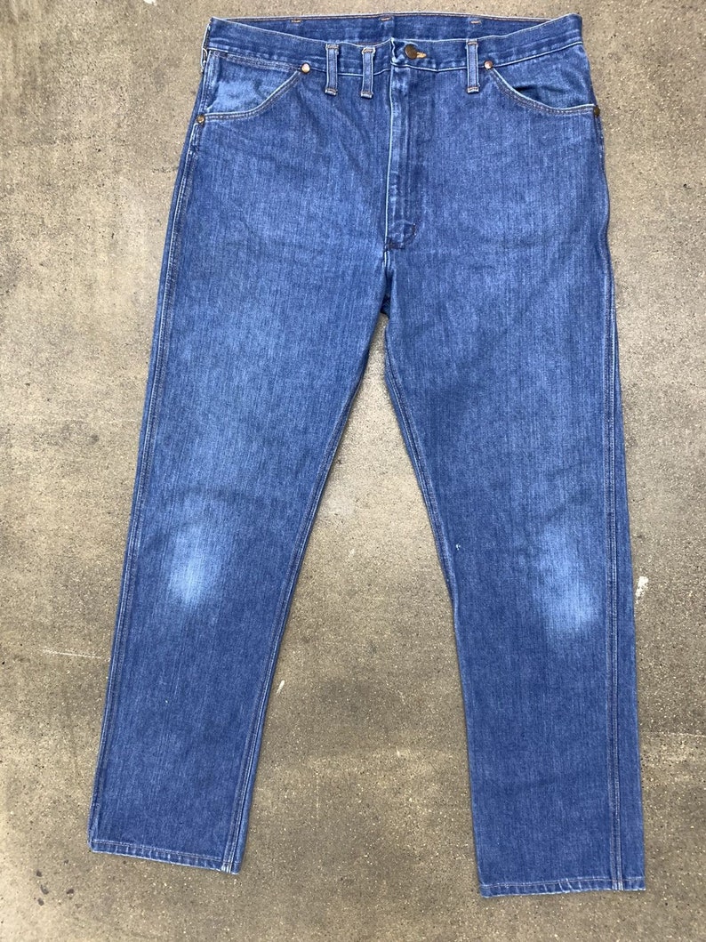 May include: A pair of blue denim jeans with a straight leg fit. The jeans have a classic five-pocket design and a button fly.