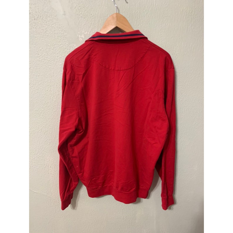 May include: A red long-sleeve shirt with a blue and red striped collar.