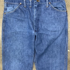 May include: A pair of blue denim jeans with a straight leg fit. The jeans have a classic five-pocket design and a button fly.