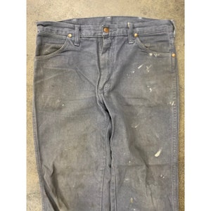 May include: A pair of dark gray denim jeans with white paint splatters. The jeans have a classic five-pocket style and a straight leg.