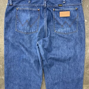 May include: A pair of blue denim jeans with a leather patch on the back pocket that says "Wrangler".