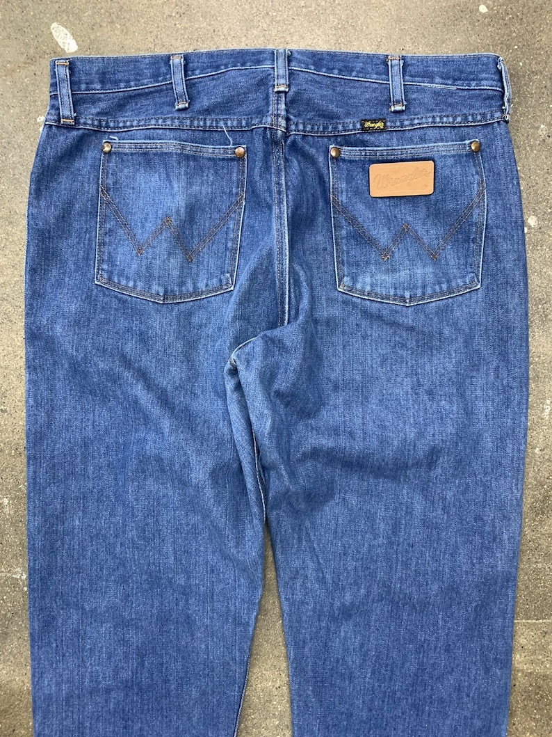 May include: A pair of blue denim jeans with a leather patch on the back pocket that says "Wrangler".