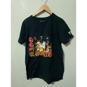 Puede incluir: Camiseta negra con un estampado gráfico de un grupo de personas frente a las llamas. El texto "OFF-WHITE GANG" está impreso en rojo y naranja en la parte delantera de la camiseta.