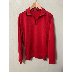 May include: A red long-sleeve sweater with a blue polo player logo and a half-zip closure. The sweater has a navy blue trim around the collar.