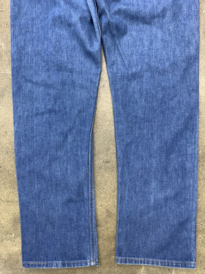 May include: A pair of blue denim jeans with a straight leg fit. The jeans have a classic five-pocket style and a button fly.