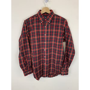 May include: A red, black, and green plaid long-sleeve button-down shirt.