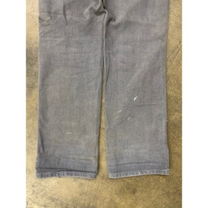 May include: A pair of dark blue denim pants with a straight leg fit. The pants have a slight sheen and are made of a durable fabric.