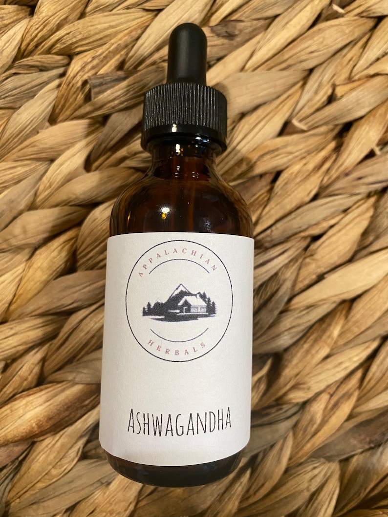 K&ouml;nnte beinhalten: Eine braune Glasflasche mit Tropfer und einem wei&szlig;en Etikett. Das Etikett zeigt ein schwarz-wei&szlig;es Logo mit einer H&uuml;tte und dem Text "Appalachian Herbals". Das Etikett tr&auml;gt auch den Text "Ashwagandha" in Schwarz.