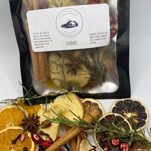 May include: A clear plastic bag filled with dried fruit, spices, and herbs for simmering. The bag is labeled "Appalachian Herbals" and "Simmer". The ingredients include dried apples, pears, oranges, lemons, cranberries, cloves, cinnamon, rosemary, and star anise.