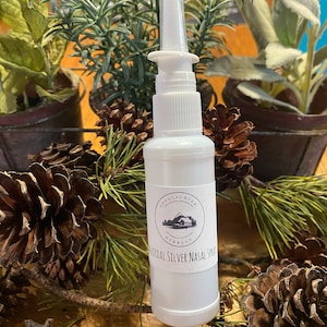 May include: A white plastic bottle with a silver spray nozzle. The bottle has a black and white label with the text "Appalachian Herbals Colloidal Silver Nasal Spray".