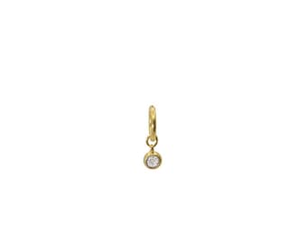 May include: A single gold-colored earring with a small, round, clear gemstone pendant. The earring is a hoop style with a hinged closure. The gemstone is set in a bezel setting and hangs freely from the hoop.