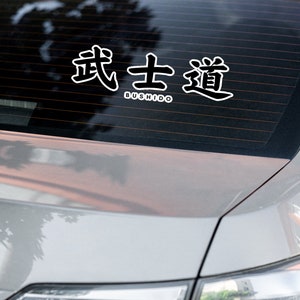 May include: A silver car with a black and white sticker on the back window that says "武士道" and "Bushido".