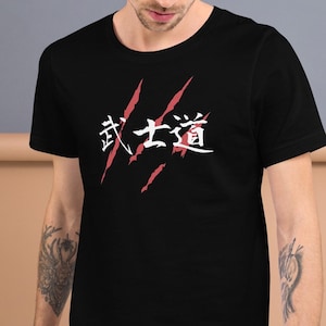 May include: Black t-shirt with white Japanese characters and red slash marks. The shirt is short-sleeved and has a crew neck. The person is wearing the shirt.
