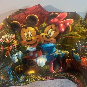 Puede incluir: Una manta de felpa colorida con Mickey Mouse y Minnie Mouse en un entorno de bosque de ensue&ntilde;o. La manta est&aacute; hecha de tela suave y tiene un esquema de color verde, rojo y amarillo vibrante.