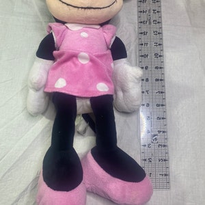 Puede incluir: Un juguete de peluche rosa y negro de un rat&oacute;n de dibujos animados que lleva un vestido rosa con lunares. El juguete mide aproximadamente 76 cm de alto.
