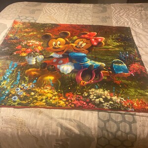 Puede incluir: Un tapiz colorido con Mickey Mouse y Minnie Mouse en un entorno de jard&iacute;n. El tapiz es una mezcla vibrante de verdes, rojos, amarillos y azules, con flores y follaje que rodean a los ic&oacute;nicos personajes de Disney.