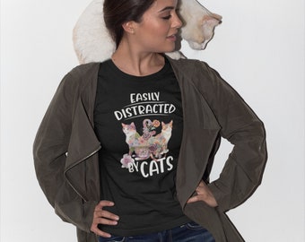 Könnte beinhalten: Ein schwarzes T-Shirt mit dem Text "Easily Distracted by Cats" und einem floralen Design mit drei Katzen.