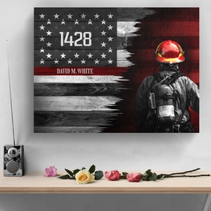 May include: A distressed American flag with a red stripe and a firefighter standing in front of it. The flag has the number "1428" and the name "DAVID M. WHITE" printed on it.