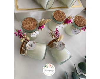 May include: Glass jar candles with cork lids, decorated with dried flowers and a small tag that says "Zize". The candles are filled with white wax and are arranged on a white surface. A sticker with the text "My Babydesign" is also visible.
