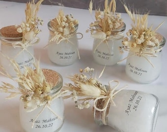 May include: A set of six small glass jars with cork lids, filled with white wax and decorated with dried flowers and wheat stalks. Each jar has a label with the text "Ayaz Mahsun 26.10.22".