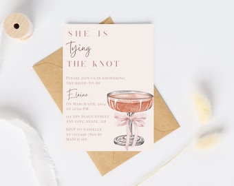 May include: A blush-colored invitation card with the text "She is Tying the Knot" and details for a bridal shower. The card features a watercolor illustration of a cocktail glass with a pink bow. An envelope and decorative elements are also visible.