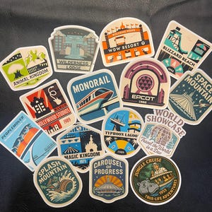 May include: A selection of colourful stickers showcasing theme park attractions. Designs include "Animal Kingdom," "Monorail," "Epcot," "Magic Kingdom," and "Jungle Cruise." Each sticker has a unique shape and vintage-inspired graphics.