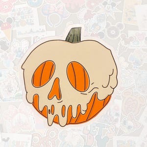 May include: A sticker featuring a stylized pumpkin with a skull-like design. The pumpkin is primarily orange with a cream-colored top that appears to be melting. The design has black outlines and a green stem. The background is filled with various stickers.