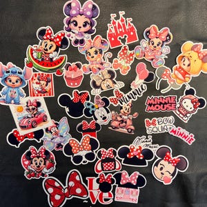 May include: A collection of colorful Minnie Mouse stickers in various poses and designs. The stickers feature Minnie Mouse with bows, strawberries, and other accessories. Some stickers include text like "Minnie Mouse" and "Boo Squad Minnie".