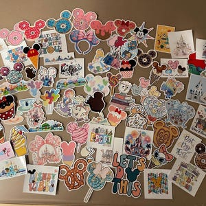 May include: A collection of colorful Disney-themed stickers featuring Mickey Mouse, Minnie Mouse, donuts, castles, and various other iconic elements. The stickers are in various shapes and sizes, with text like "Let's Do This" and "Disney Vibes".