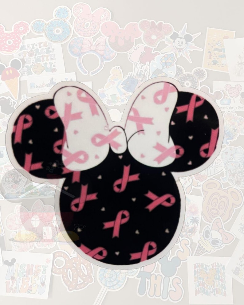 K&ouml;nnte beinhalten: Ein Minnie-Mouse-f&ouml;rmiger Aufkleber mit schwarzem Kopf und Ohren und einer wei&szlig;en Schleife. Die Schleife ist mit rosa B&auml;ndern verziert, und der Kopf ist mit rosa B&auml;ndern und kleinen wei&szlig;en Herzen bedeckt. Der Aufkleber ist von anderen Aufklebern umgeben.
