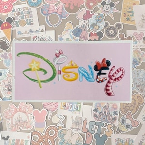 May include: A collection of Disney-themed stickers and decals. The central sticker features the Disney logo in colorful, stylized lettering. Surrounding the logo are various stickers with Mickey Mouse ears, castles, and phrases like "May the Force Be With You".