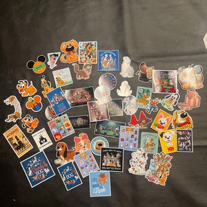 May include: A collection of colorful stickers featuring various cartoon dogs. Designs include Pluto, Lady and the Tramp, 101 Dalmatians, and other Disney characters. Some stickers have text like "100% Cute" and "Beware".